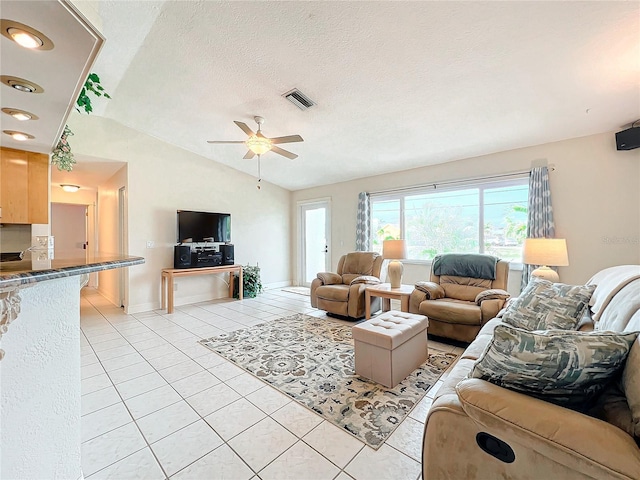 living room with a textured ceiling, ceiling fan, light tile patterned floors, and lofted ceiling