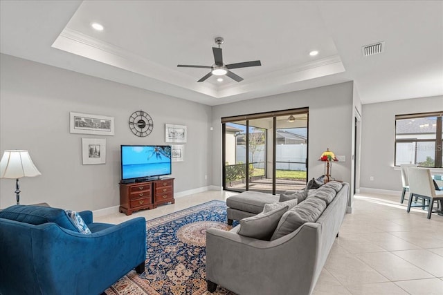 tiled living room with a tray ceiling, a wealth of natural light, and ornamental molding