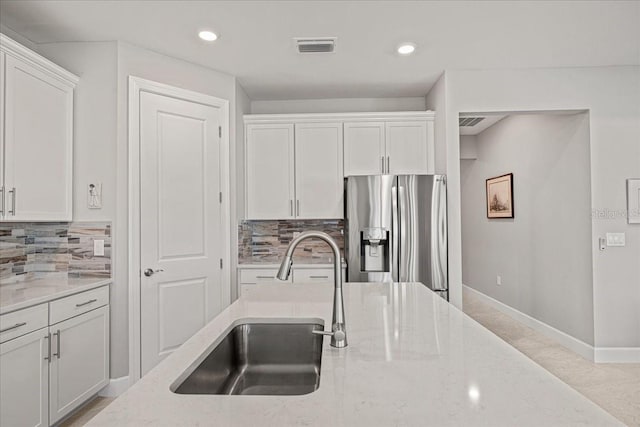 kitchen featuring stainless steel fridge with ice dispenser, white cabinetry, and sink