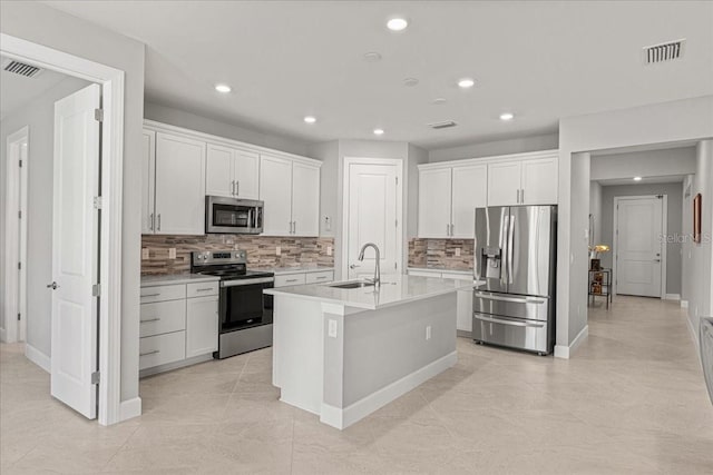 kitchen with white cabinetry, sink, tasteful backsplash, a center island with sink, and appliances with stainless steel finishes