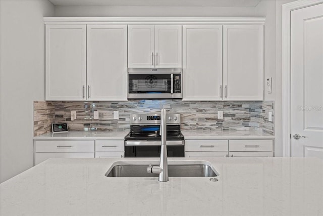 kitchen featuring stainless steel appliances, white cabinetry, and light stone counters