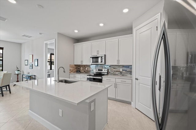 kitchen featuring white cabinetry, sink, light stone countertops, a center island with sink, and appliances with stainless steel finishes