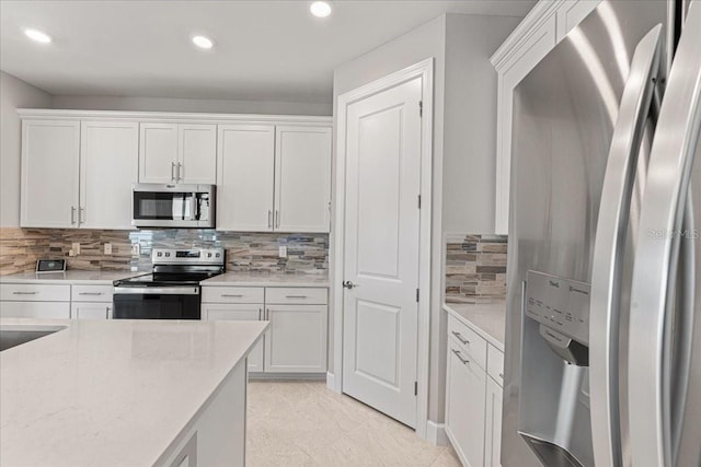 kitchen featuring decorative backsplash, appliances with stainless steel finishes, light stone counters, light tile patterned floors, and white cabinetry