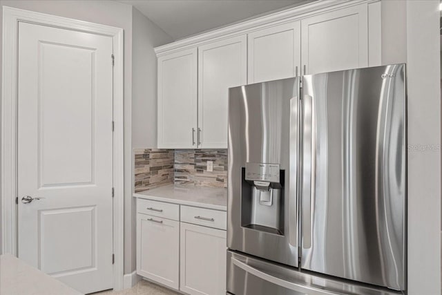 kitchen featuring white cabinets, stainless steel refrigerator with ice dispenser, and tasteful backsplash