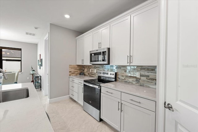 kitchen featuring backsplash, stainless steel appliances, sink, light tile patterned floors, and white cabinets