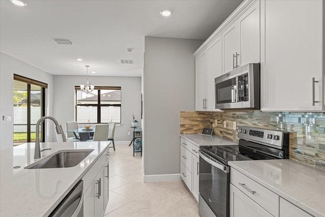 kitchen featuring decorative backsplash, appliances with stainless steel finishes, sink, light tile patterned floors, and white cabinets