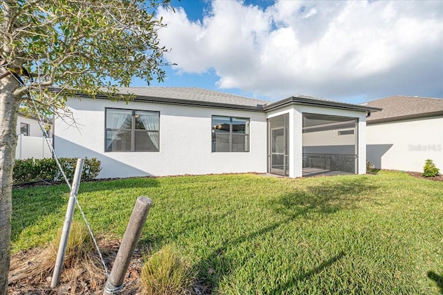 back of property featuring a lawn and a sunroom