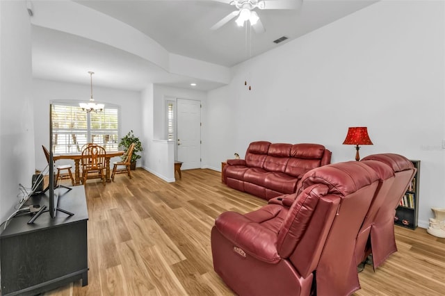 living room featuring lofted ceiling, hardwood / wood-style floors, and ceiling fan with notable chandelier