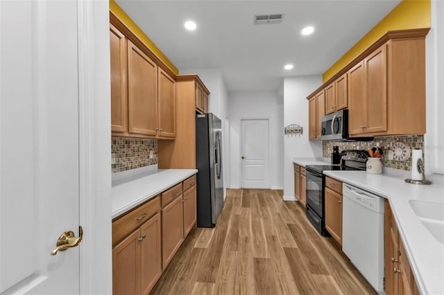 kitchen with backsplash, sink, stainless steel appliances, and light hardwood / wood-style floors