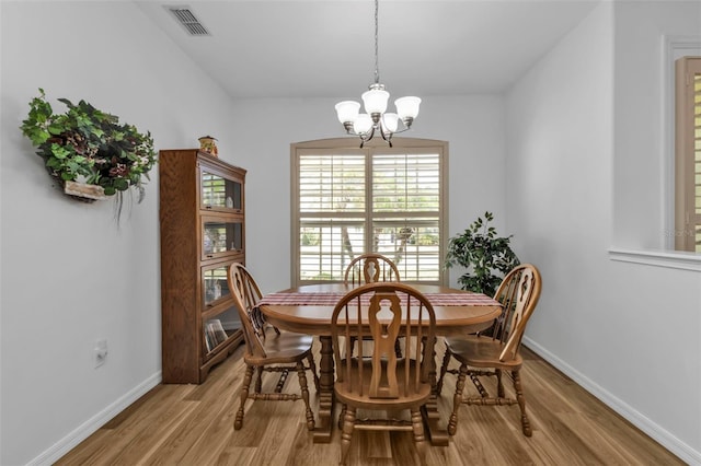 dining area with light wood-type flooring and an inviting chandelier