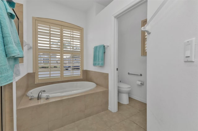 bathroom featuring tile patterned floors, tiled bath, and toilet