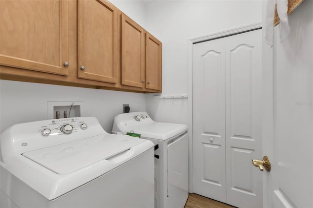 laundry area featuring washing machine and dryer, cabinets, and light hardwood / wood-style floors