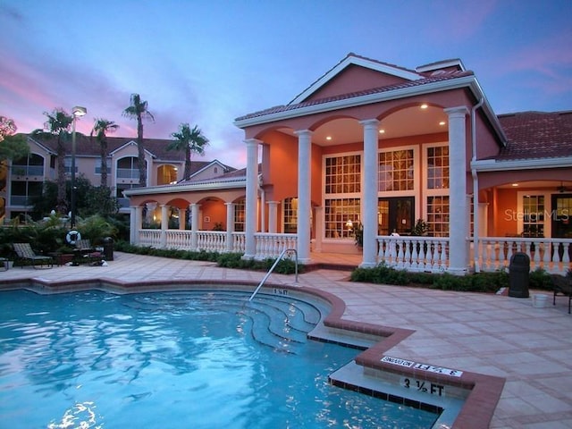 pool at dusk featuring a patio