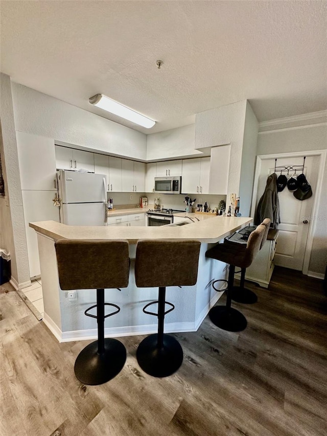 kitchen featuring kitchen peninsula, appliances with stainless steel finishes, a textured ceiling, and white cabinetry