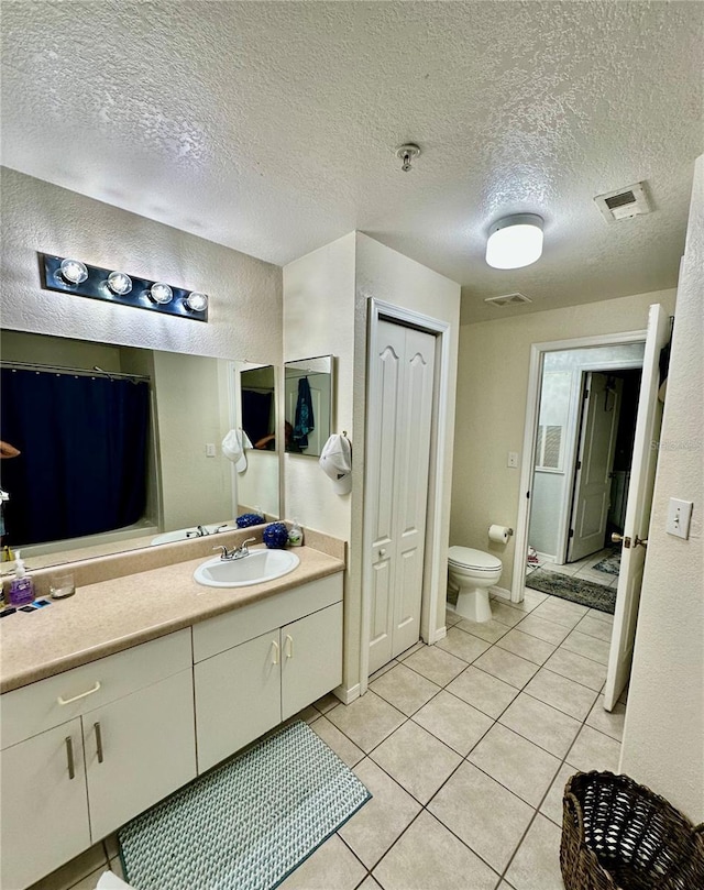 bathroom featuring tile patterned floors, vanity, toilet, and a textured ceiling