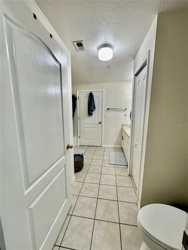 bathroom featuring tile patterned floors, a textured ceiling, and toilet