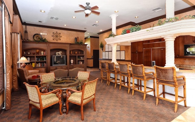 carpeted dining area with ornate columns, ceiling fan, and ornamental molding