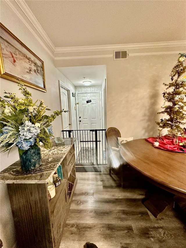 dining space featuring visible vents, crown molding, and wood finished floors