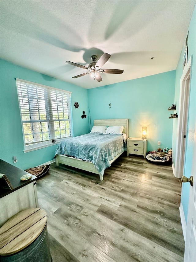 bedroom featuring a textured ceiling, wood finished floors, a ceiling fan, and baseboards