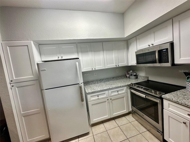 kitchen with light stone countertops, light tile patterned floors, and appliances with stainless steel finishes