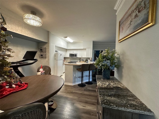 kitchen featuring a textured wall, appliances with stainless steel finishes, dark wood-type flooring, white cabinets, and a peninsula