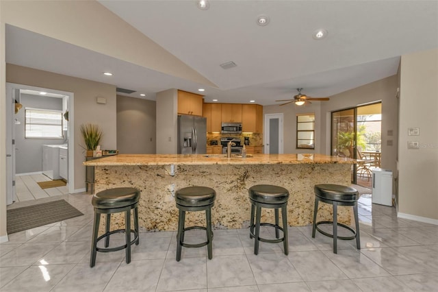 kitchen featuring a breakfast bar area, sink, lofted ceiling, and appliances with stainless steel finishes