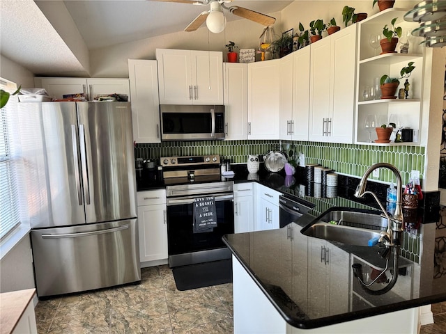 kitchen featuring white cabinets, sink, vaulted ceiling, dark stone countertops, and appliances with stainless steel finishes