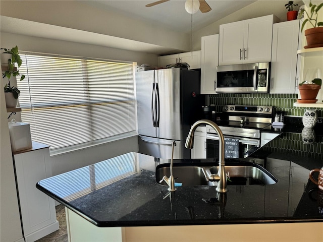 kitchen with appliances with stainless steel finishes, vaulted ceiling, white cabinetry, and sink