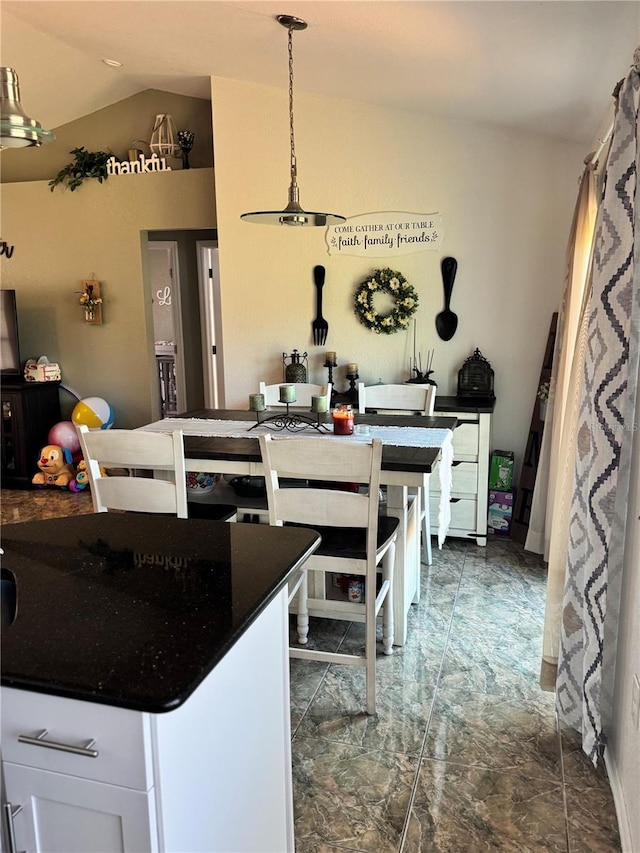 kitchen with white cabinets, hanging light fixtures, and lofted ceiling