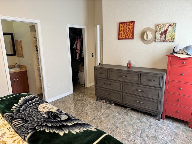 bedroom featuring a walk in closet, ensuite bathroom, a closet, and sink