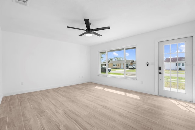 empty room with ceiling fan, plenty of natural light, and light wood-type flooring