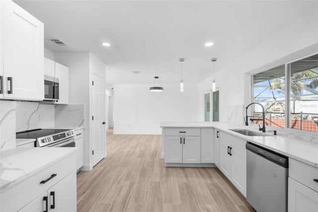 kitchen with white cabinetry, sink, hanging light fixtures, and appliances with stainless steel finishes