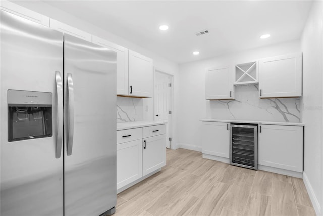 kitchen featuring decorative backsplash, stainless steel refrigerator with ice dispenser, white cabinets, and beverage cooler