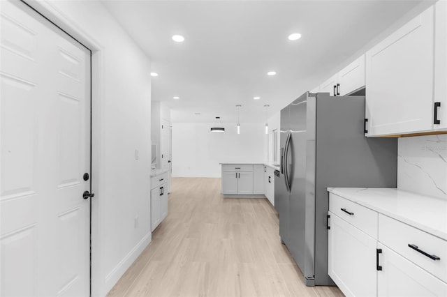 kitchen with light stone countertops, stainless steel fridge, tasteful backsplash, and white cabinetry