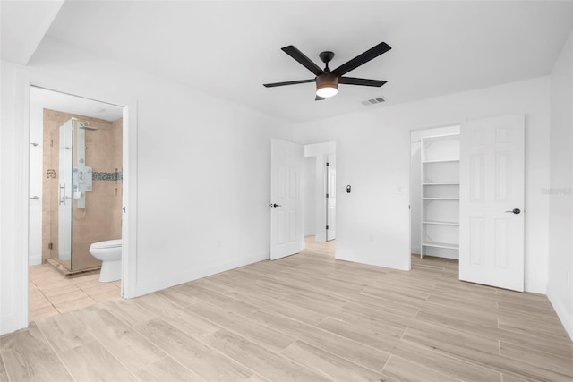 unfurnished bedroom with connected bathroom, a spacious closet, ceiling fan, light hardwood / wood-style flooring, and a closet