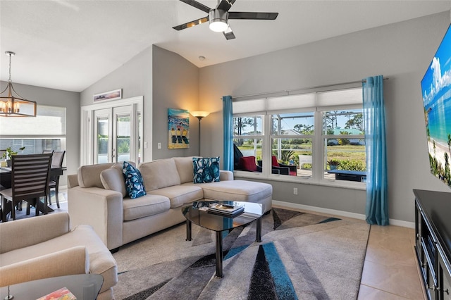 tiled living room with ceiling fan with notable chandelier and lofted ceiling