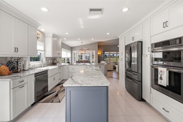 kitchen featuring kitchen peninsula, vaulted ceiling, decorative backsplash, white cabinets, and appliances with stainless steel finishes