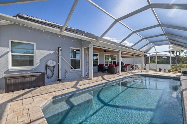 view of pool with outdoor lounge area, a patio, glass enclosure, and ceiling fan