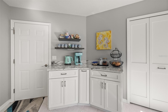 bar featuring white cabinetry and light stone counters