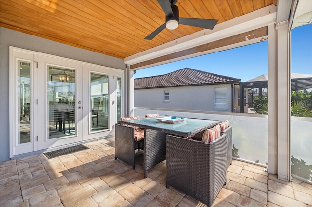 view of patio / terrace with glass enclosure, french doors, outdoor dining area, and a ceiling fan