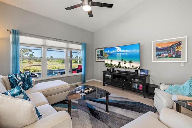 living area with a ceiling fan, light tile patterned flooring, vaulted ceiling, and baseboards