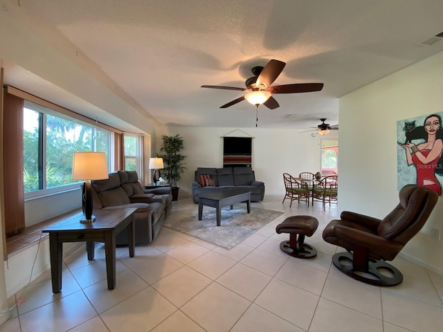 living room featuring a textured ceiling, ceiling fan, and light tile patterned flooring