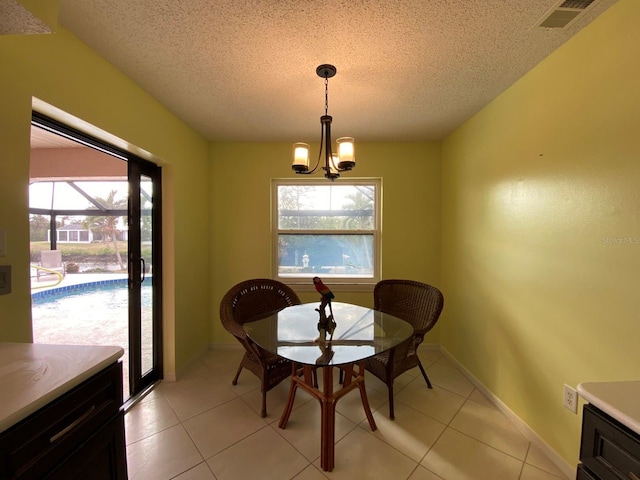 dining area with a textured ceiling, an inviting chandelier, a healthy amount of sunlight, and light tile patterned flooring