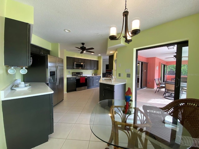 kitchen featuring sink, pendant lighting, light tile patterned floors, ceiling fan with notable chandelier, and appliances with stainless steel finishes