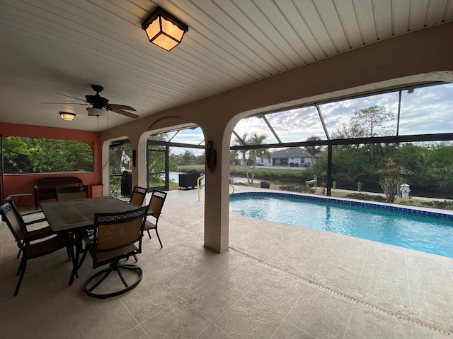 view of pool featuring glass enclosure, ceiling fan, and a patio