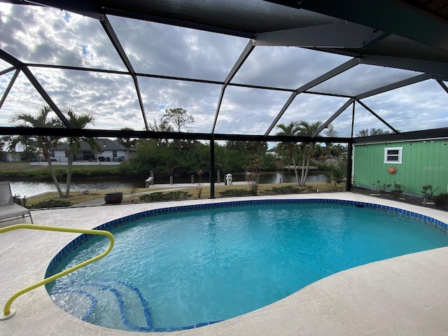 view of swimming pool with glass enclosure and a water view