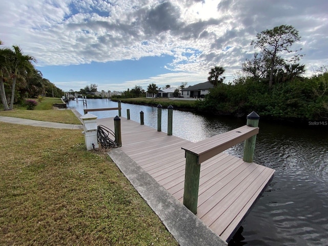 view of dock with a water view and a yard