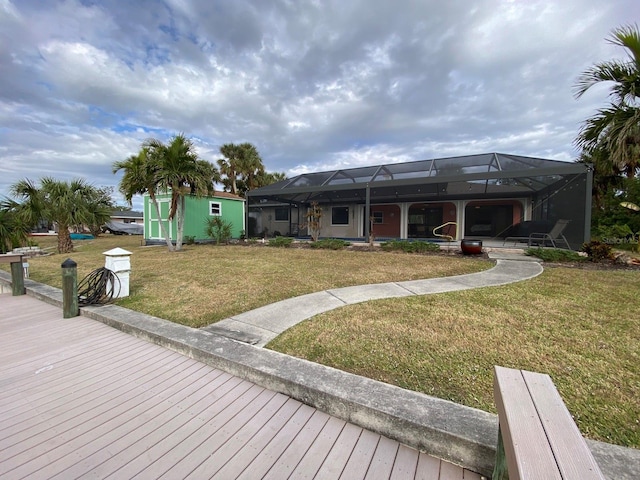 back of house featuring glass enclosure, a yard, and a shed