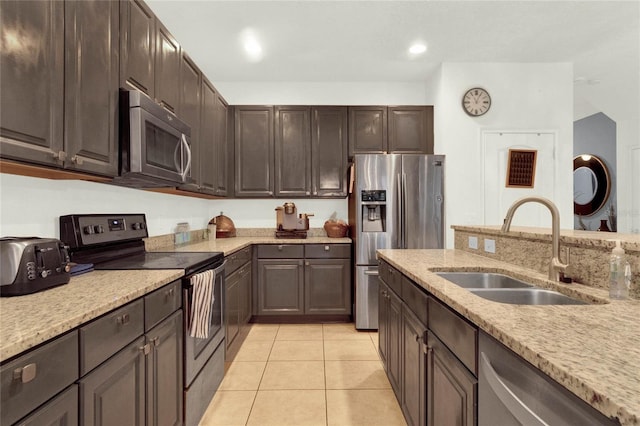 kitchen with dark brown cabinetry, light stone countertops, sink, stainless steel appliances, and light tile patterned floors