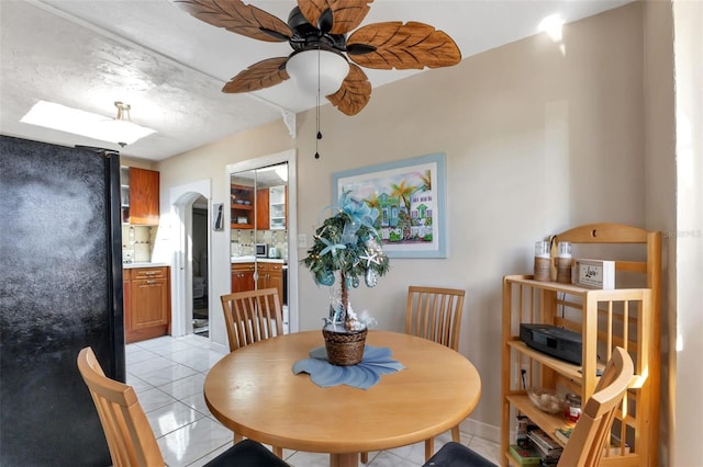 tiled dining area featuring a textured ceiling, a skylight, and ceiling fan